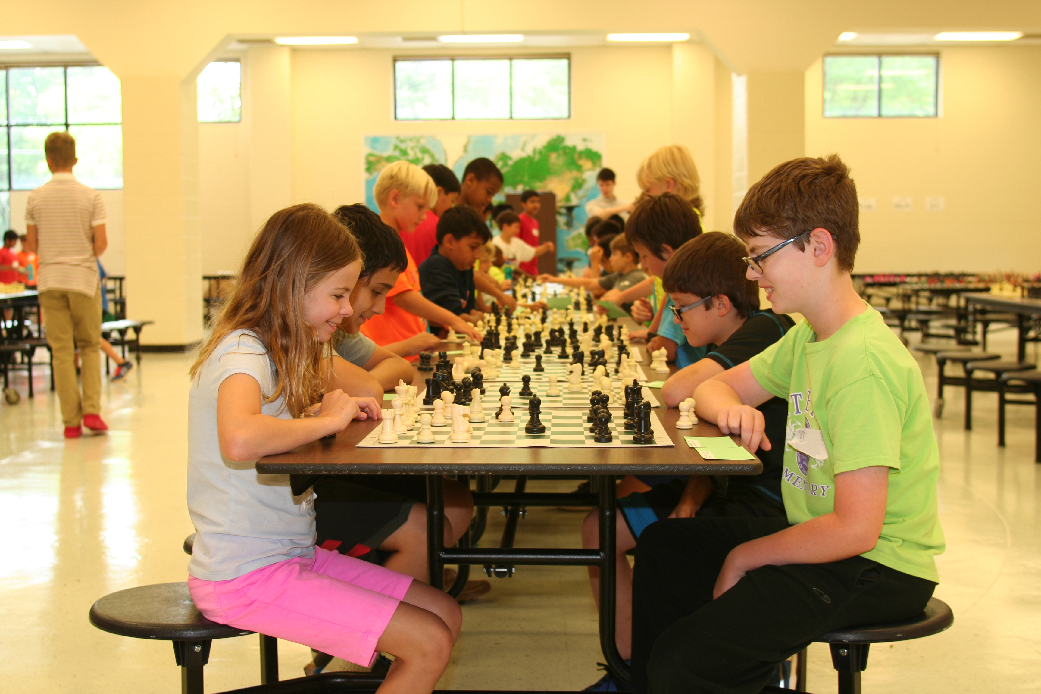 a group of kids playing chess at school.
